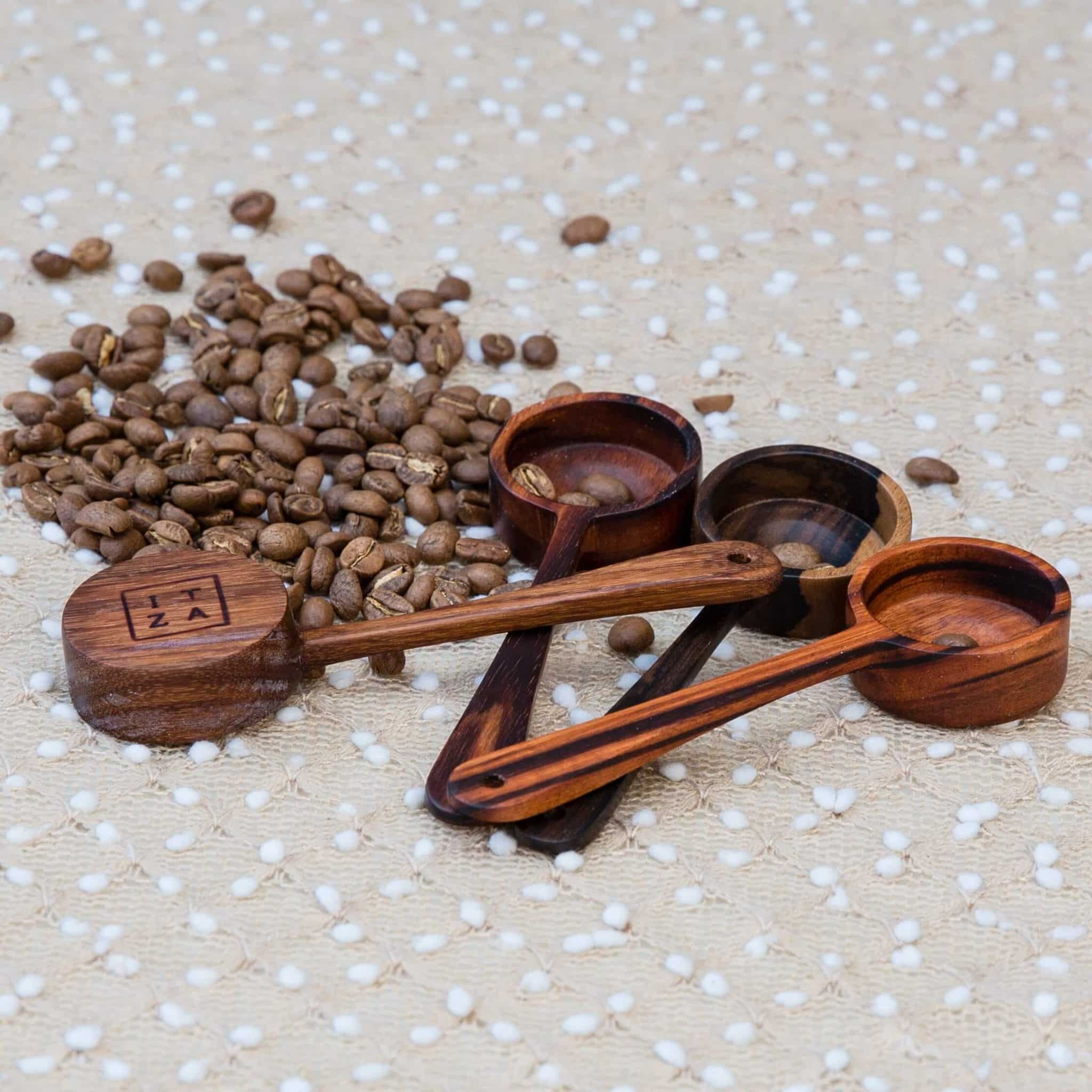 4 coffee scoops with beans Four wooden coffee scoops made by skilled artisans in Guatemala, surrounded by coffee beans