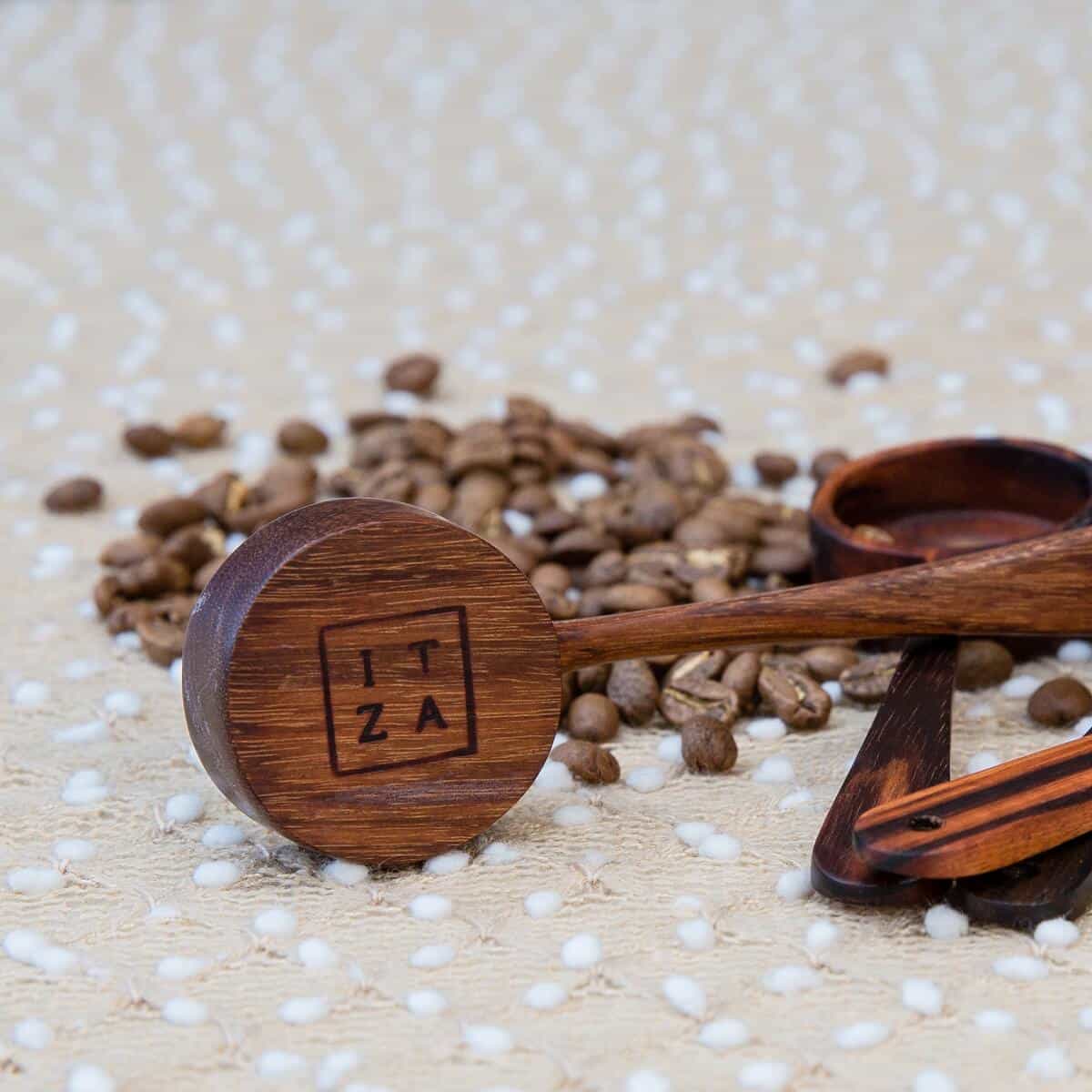 view of Itza logo under coffee scoop sideview of handmade wooden coffee scoop that says "itza" on the side