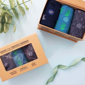 Two boxes displaying three pairs of socks each, featuring assorted colors and patterns