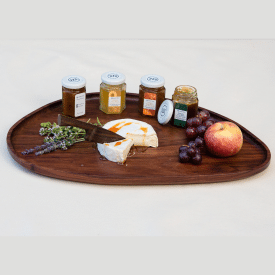 Handcrafted large wooden leaf-shaped tray curated with gourmet cheeses, fresh fruit, and artisanal jams