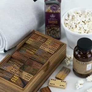 Corporate gifts that give back Custom holiday gifts: A gift set comprised of handmade dominoes in an engravable box, popcorn, and a rolled blanked made from recycled bottles