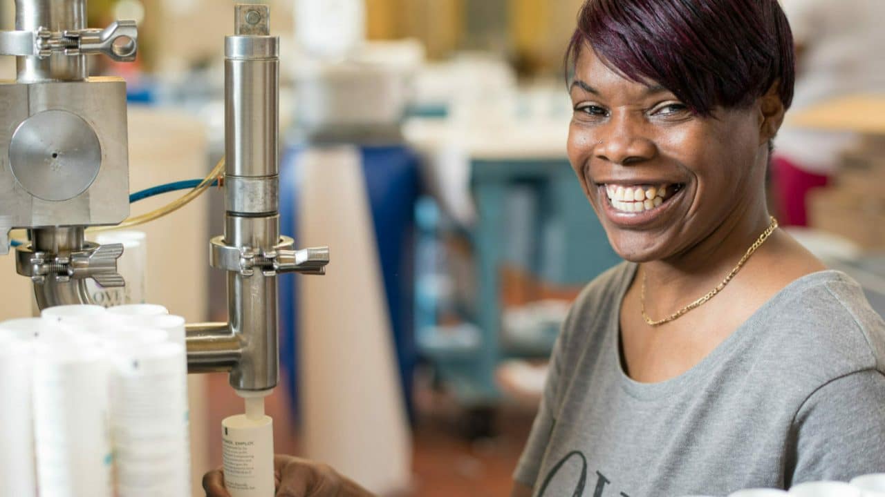 An idea for meaningful gifts for employees: Here, an employee at Thistle Farms, which employs survivors of trafficking, prostitution, and addiction, smiles as she creates a salt body scrub.