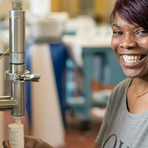An idea for meaningful gifts for employees: Here, an employee at Thistle Farms, which employs survivors of trafficking, prostitution, and addiction, smiles as she creates a salt body scrub.