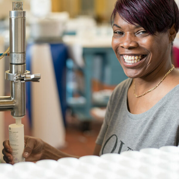 Candles for coworkers are lovingly made by Thistle Farms employees, like this woman shown smiling.