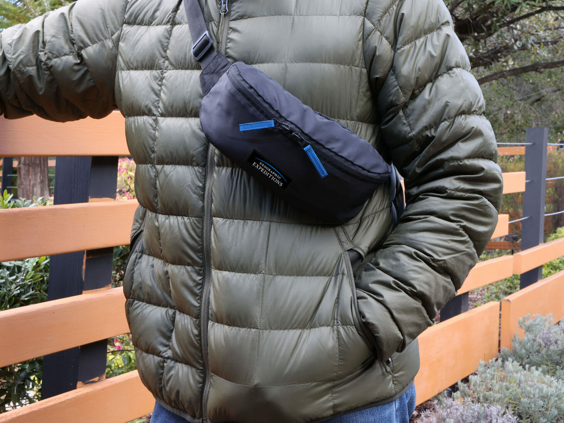 A crossbody bag is worn across the chest of a traveler in a winter coat.