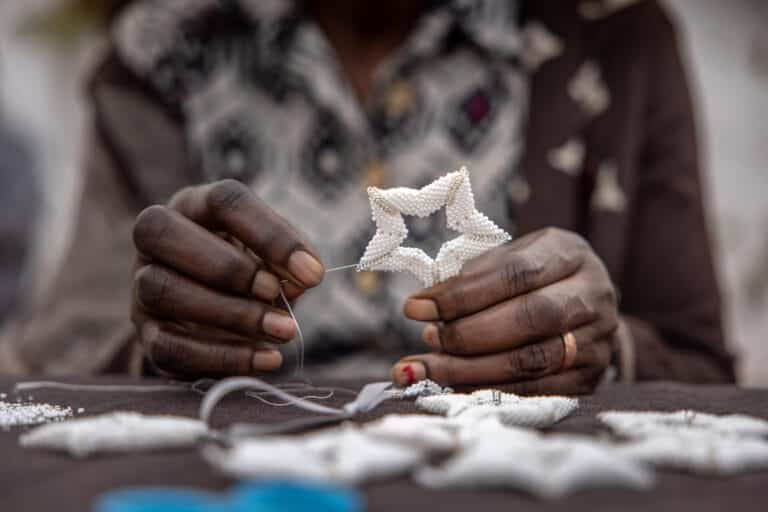 Pair of hands making a beaded star holiday ornament