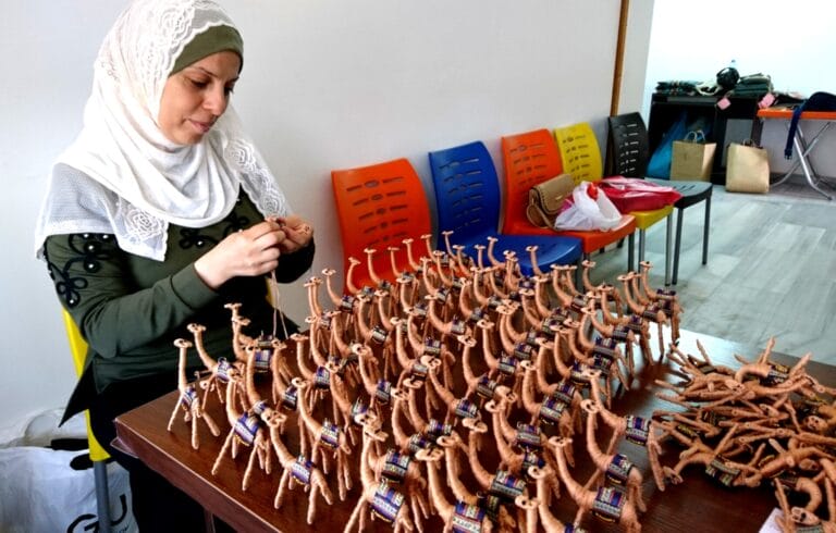 An artisan with rows of handmade camel ornaments