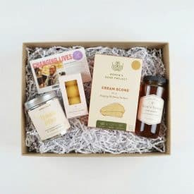comfort and care white background a birds eye view of a gift set featuring tea, scone mix, honey, and a candle made from honey along with an impact card telling about the makers