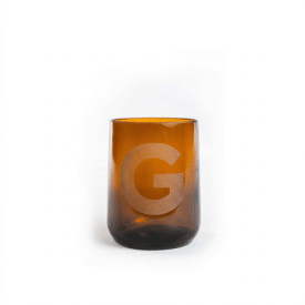 Grønn beer bottle glass with sandblast mockup A small amber-colored glass with a sandblasted "G" logo on the front