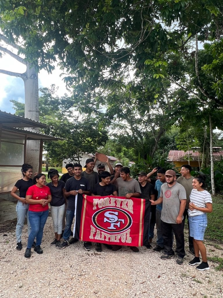 artisans who made donor gifts for the 49ers Foundation gathered with a flag that says Forever Faithful