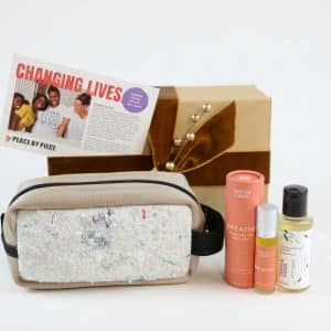 A gift set including an upcycled cream colored pouch, essential oils, and body wash make a unique wellness gift for employees for the holidays