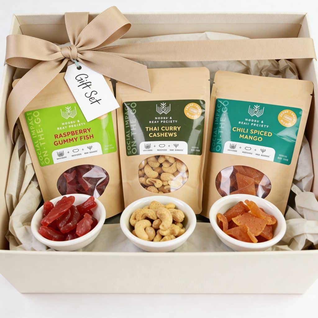 Three delicious snacks that support women - raspberry gummy fish, thai curry cashews, and chili spiced mango - are placed in a gift box as an International Women's Day gift