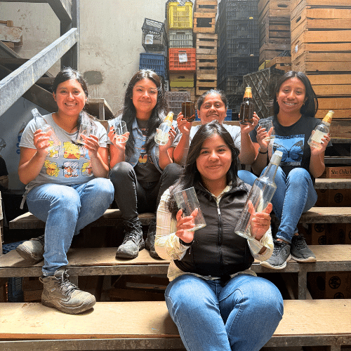 5 women sitting on stairs holding upcycled and unique glasses they make -- great International Women's Day gifts
