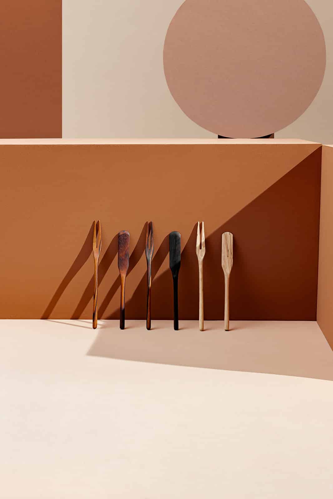 Itza Wood picks and spreaders a mix of handcrafted wooden picks and spreaders are leaned up against a brown background with warm lighting and dramatic shadows